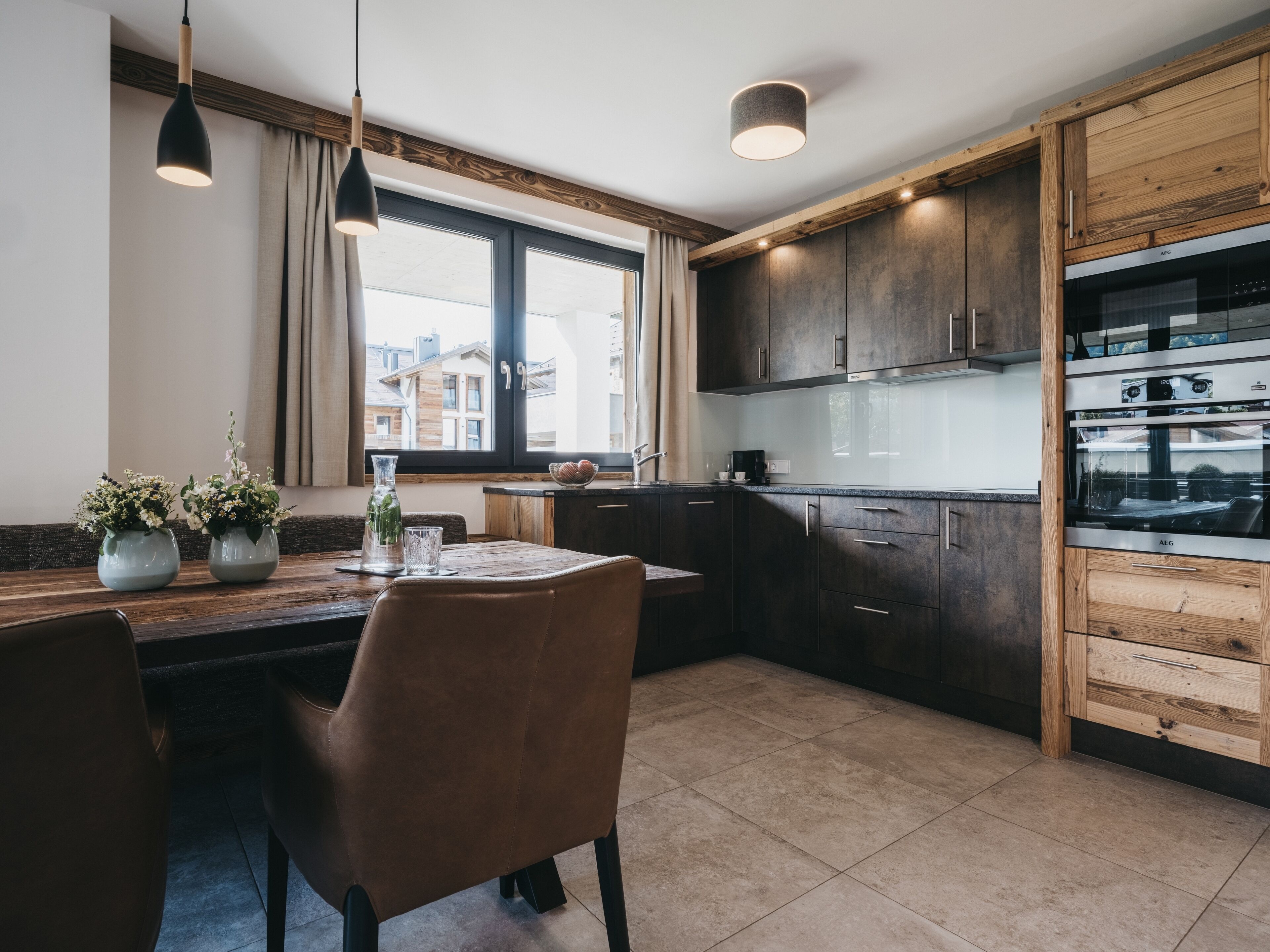 A modern kitchen with dark wooden cabinets, a built-in oven, and pendant lighting.