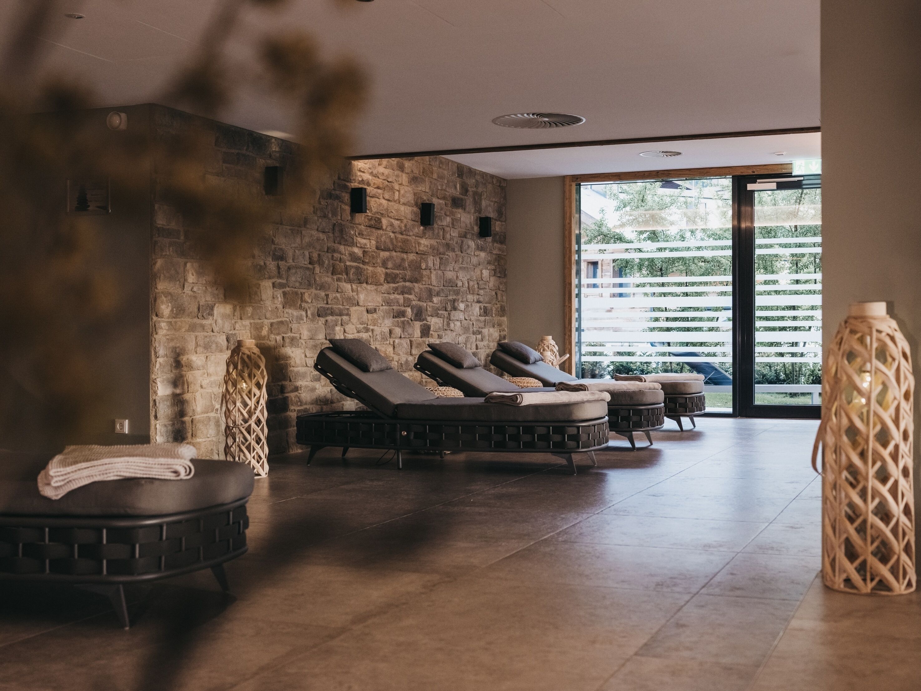 A spa area with massage chairs, a stone wall, and a large window with a view of greenery.