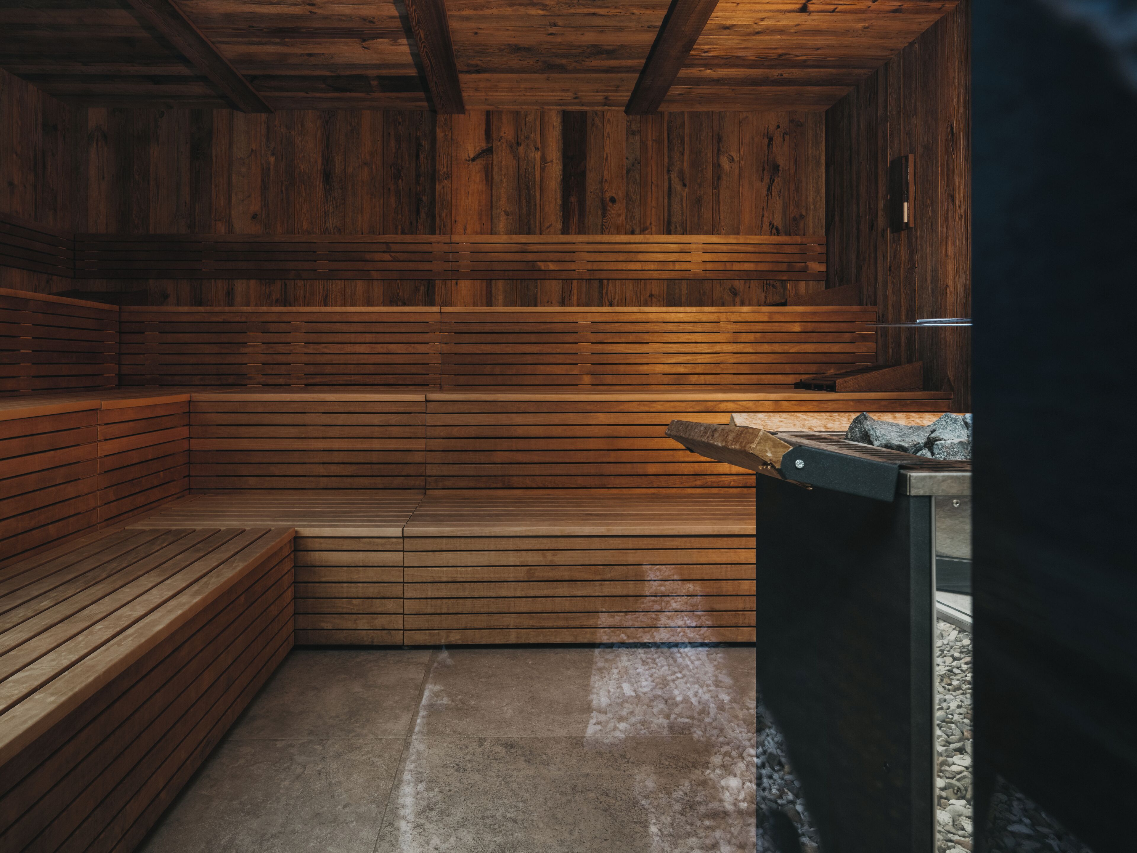 A sauna with wooden benches and a stone floor.