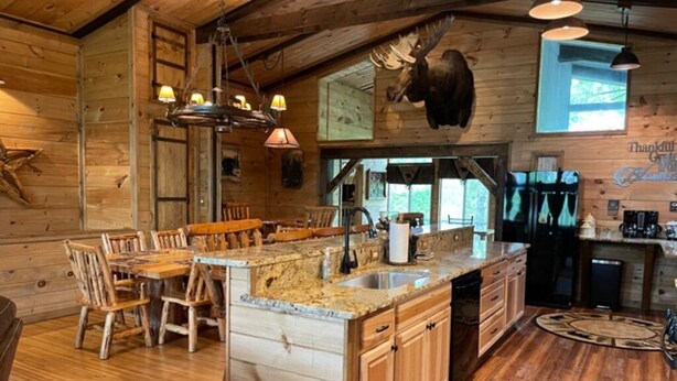 A rustic cabin interior with a wooden dining area, granite countertops, and a moose head mounted on the wall. - NEW Games Added! Spacious Lodge, Theater Rm, NFL Sunday, 2 Pools, & FishingPond (Sevierville)