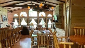 A rustic wooden dining area with high ceilings and large windows. - NEW Games Added! Spacious Lodge, Theater Rm, NFL Sunday, 2 Pools, & FishingPond (Sevierville)