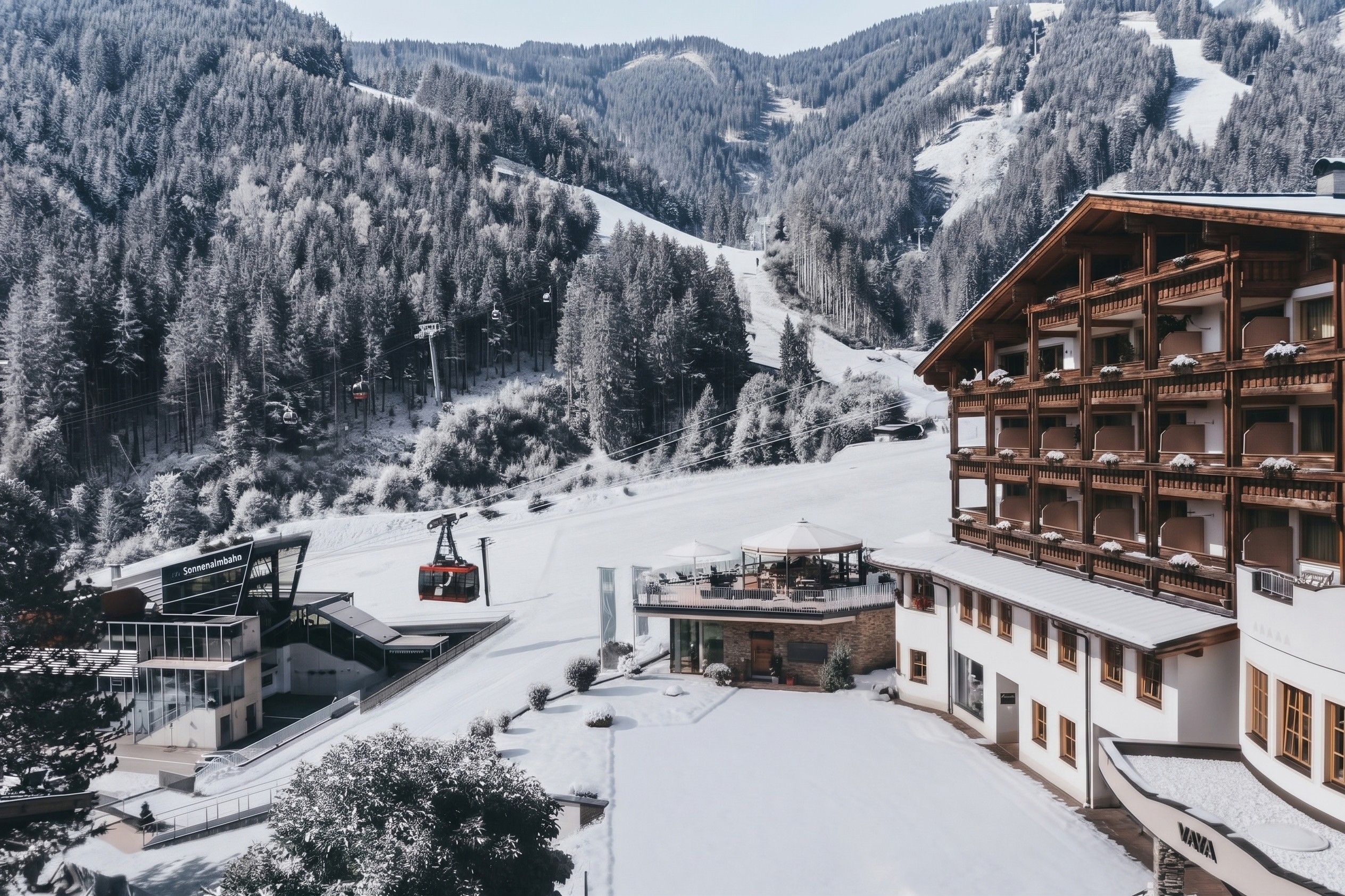 A ski resort with a cable car system, a building with multiple balconies, and a snowy mountain backdrop.