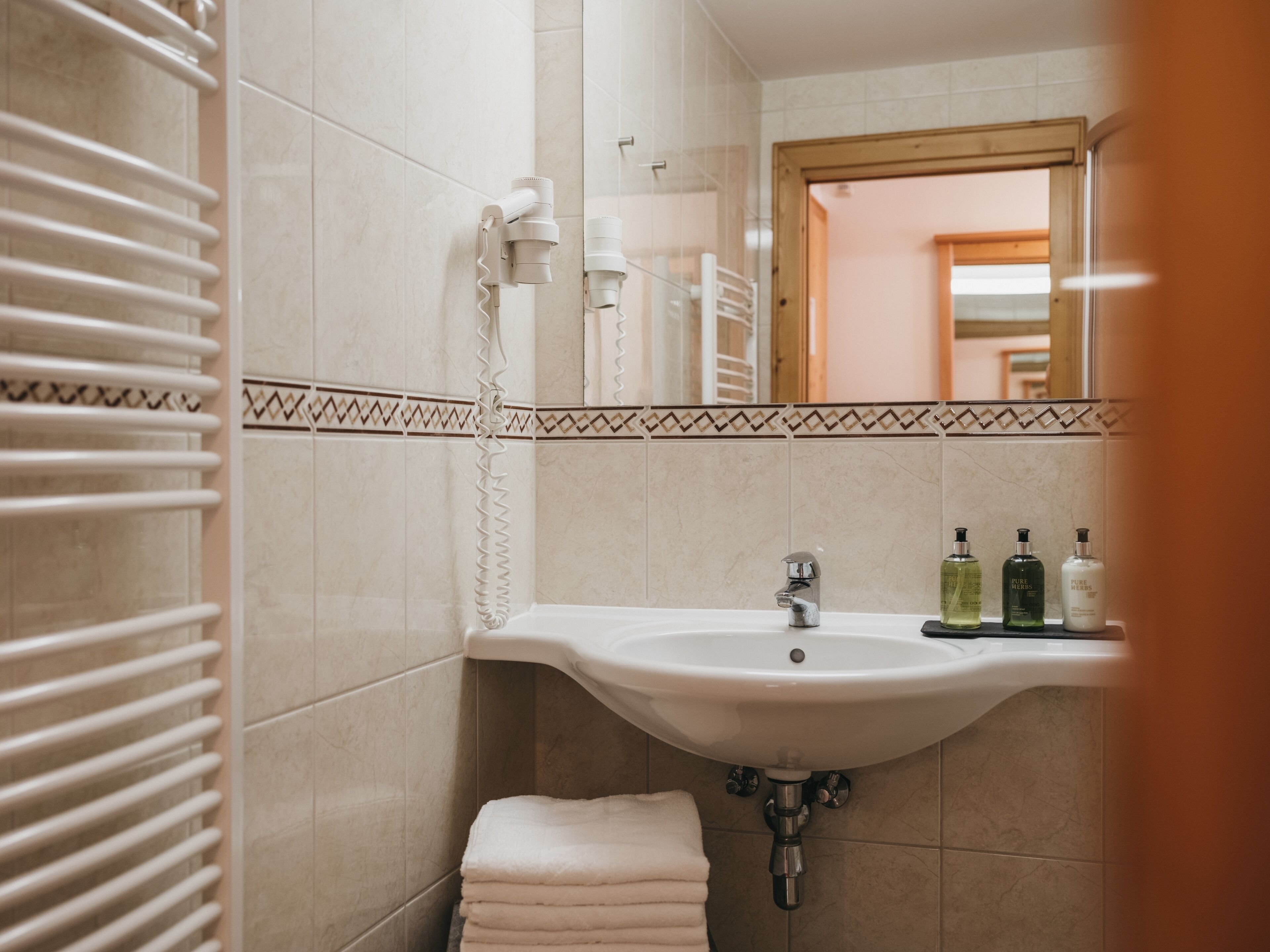 A bathroom with a white sink, a towel rack, and a mirror.