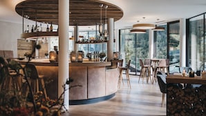 Een modern interieur met een gebogen bar, houten vloeren en grote ramen met uitzicht op het omliggende landschap.