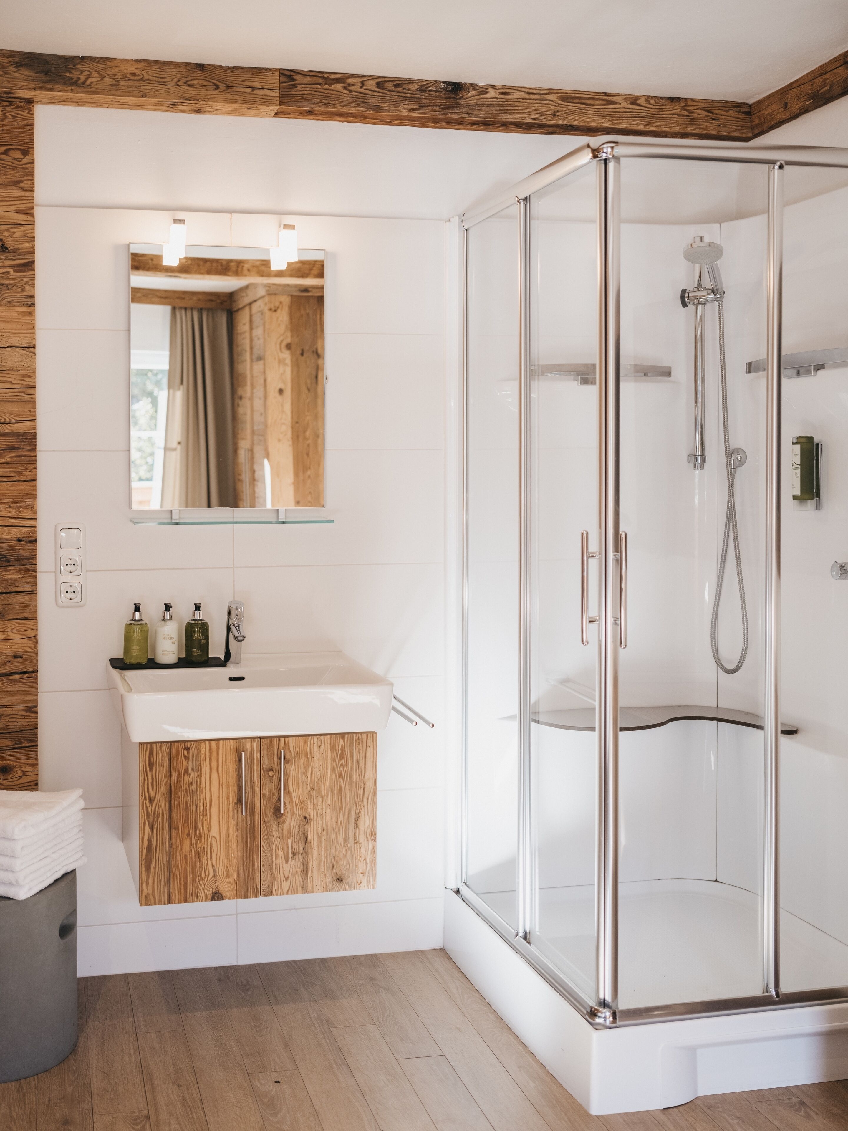 Une salle de bain moderne avec un meuble-lavabo en bois, une cabine de douche en verre et un miroir avec éclairage intégré.