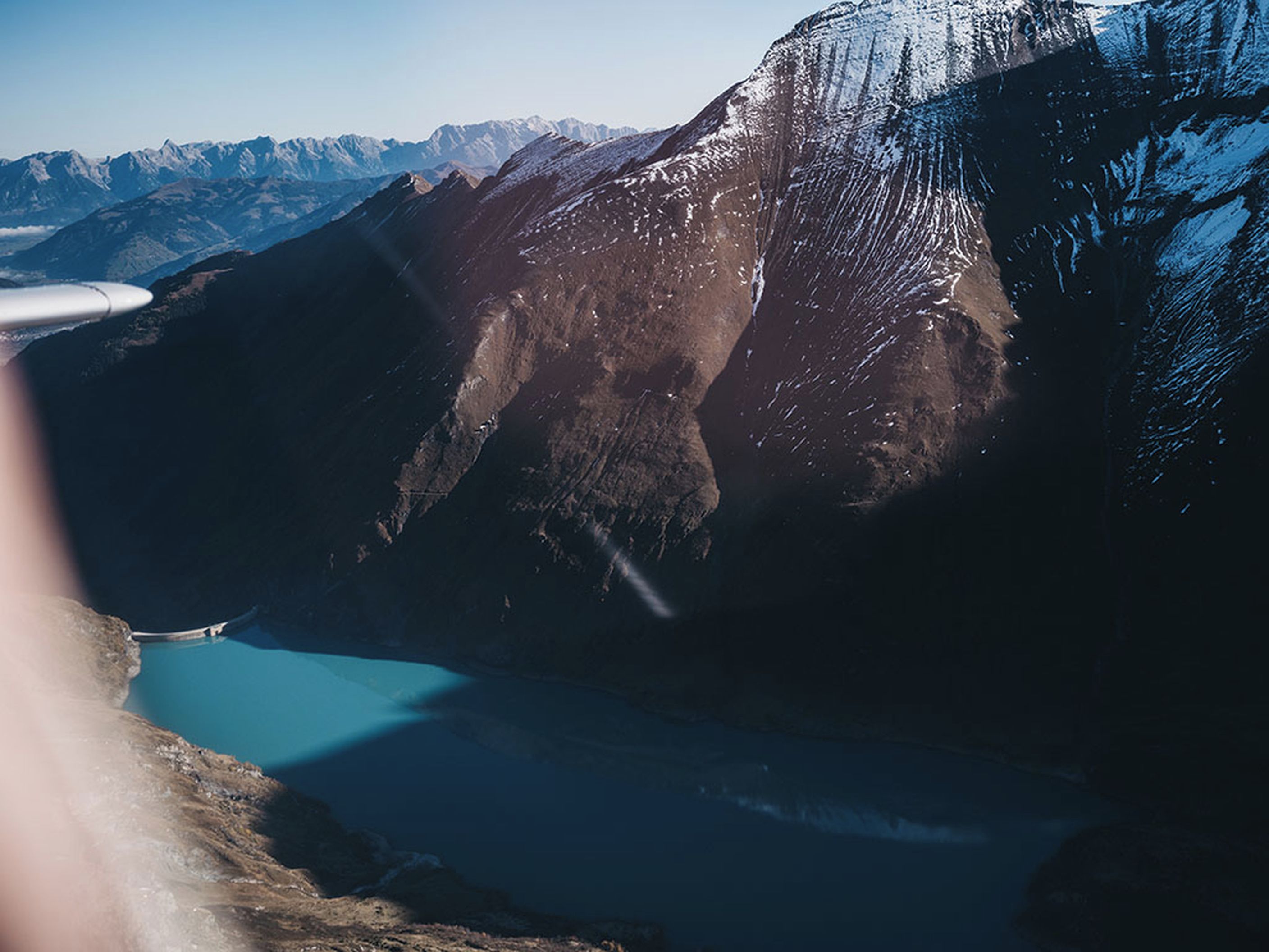 Eine gebirgige Landschaft mit klarem Himmel, einem See und einem schneebedeckten Gipfel.