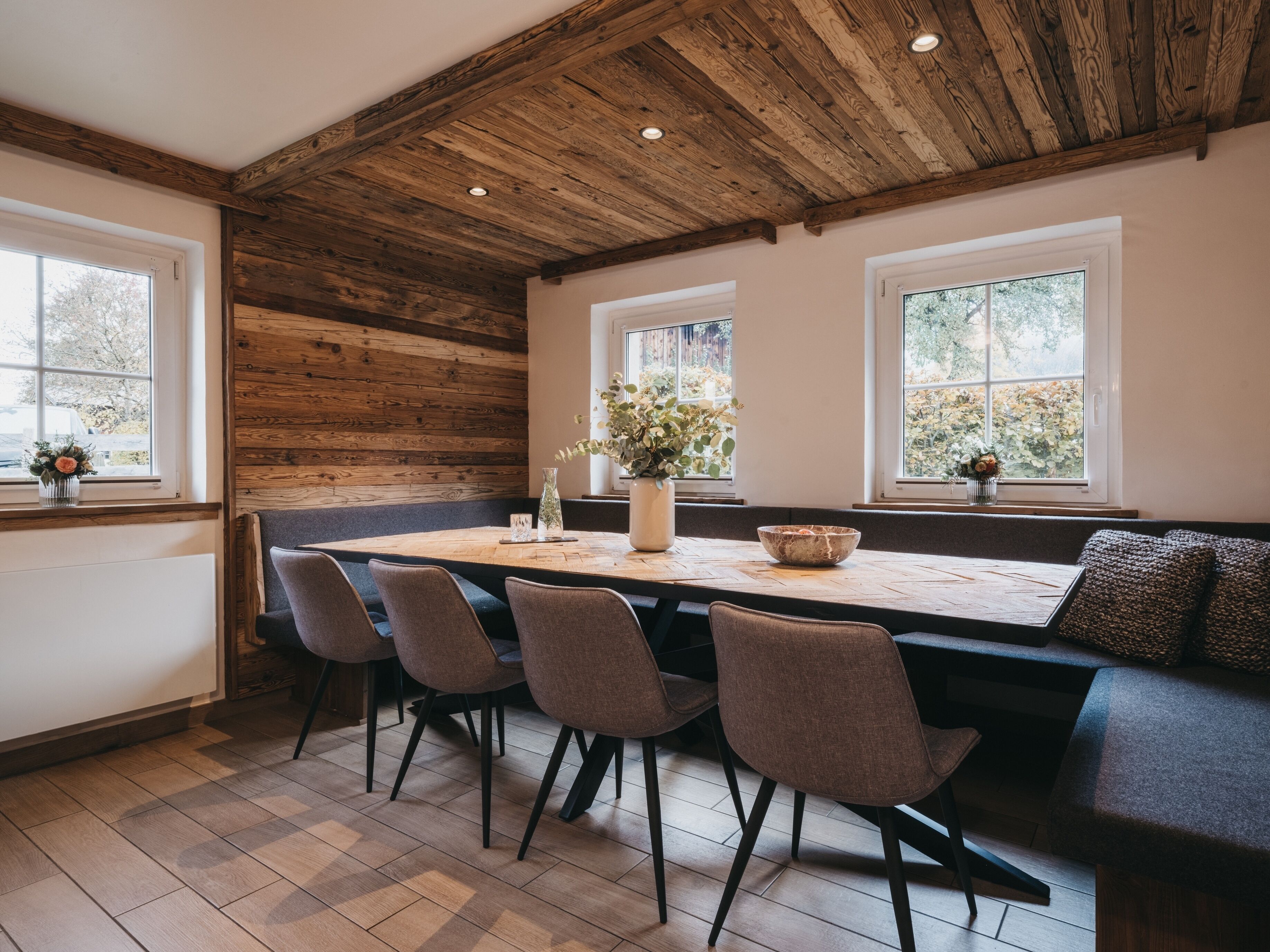 A dining area with a wooden ceiling, a long table, and four chairs.