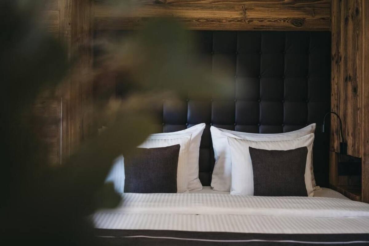 A bed with a tufted headboard, white bedding, and two pillows.