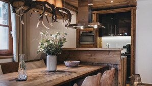 A wooden dining table with chairs, a vase with flowers, and a bowl. - VAYA Kaprun (Kaprun)