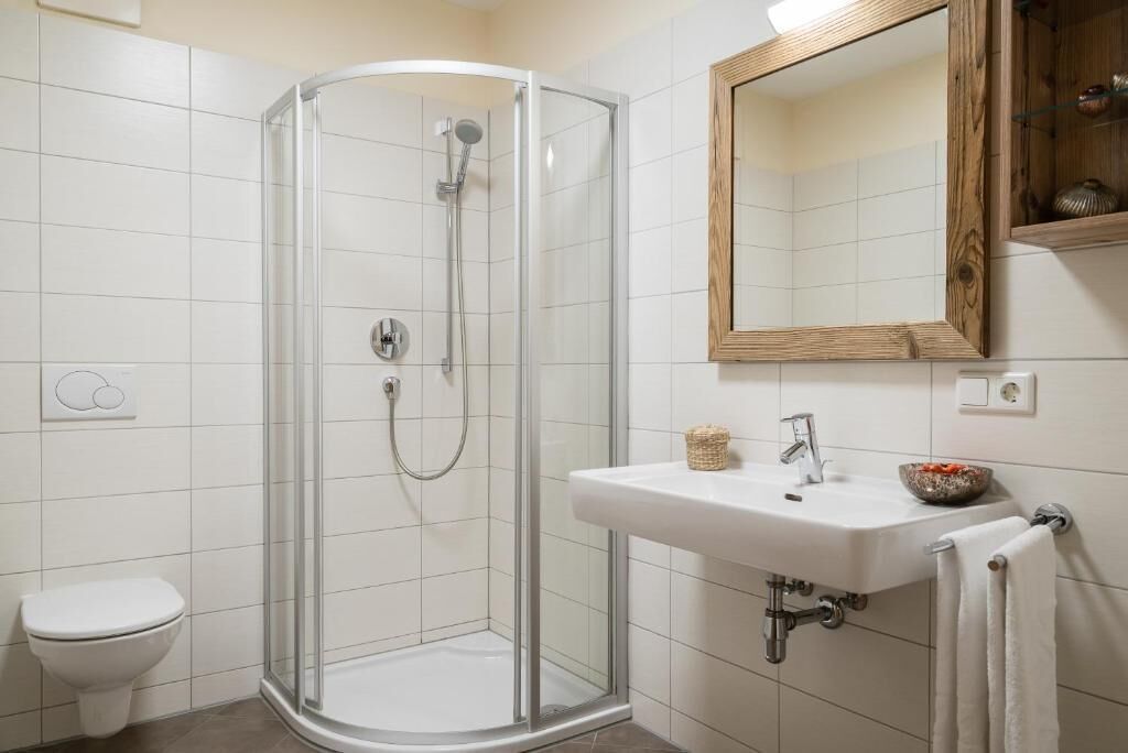 A bathroom with a glass shower enclosure, a white sink, and a mirror.