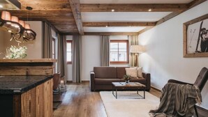 A cozy living room with a wooden ceiling, a brown sofa, a coffee table, and a rug. - VAYA Kaprun (Kaprun)