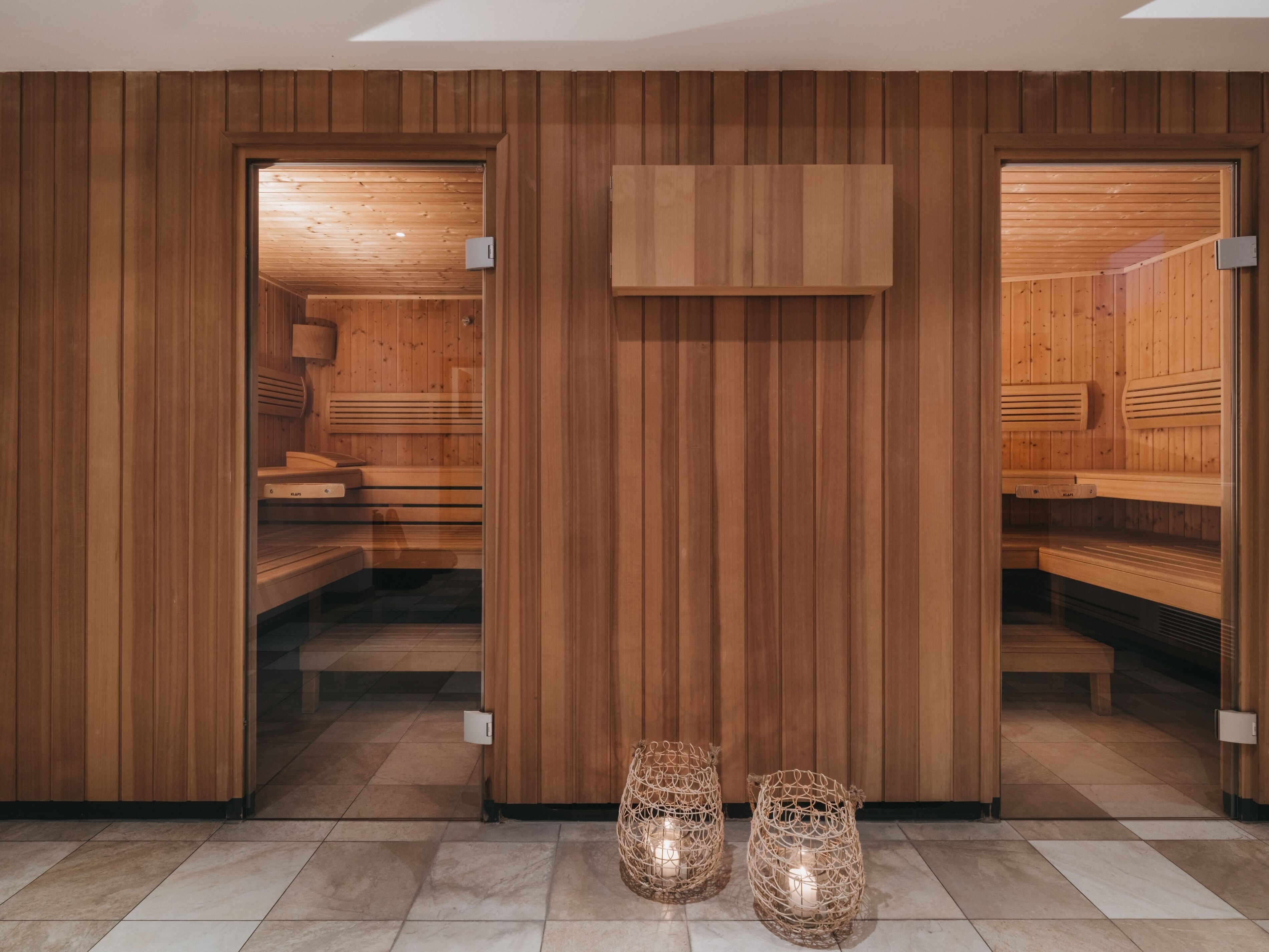 A sauna room with wooden walls and benches, a wooden ceiling, and a tiled floor.