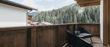 Una terraza de madera con vista a una cadena montañosa boscosa.