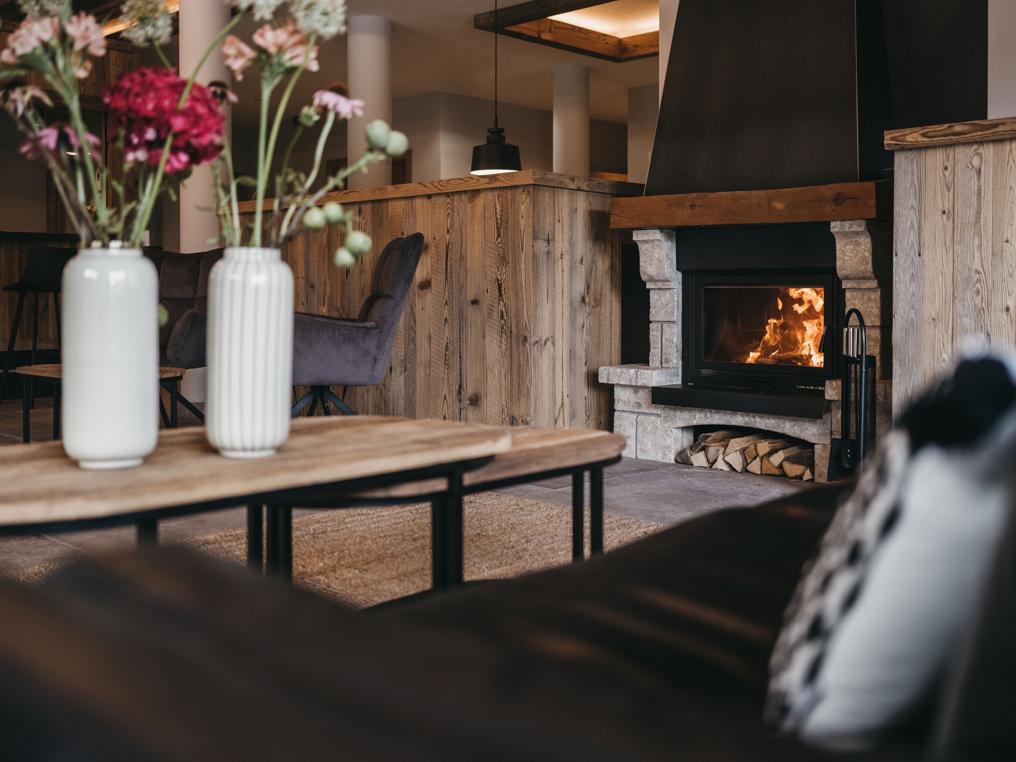 Ein gemütlicher Wohnbereich mit Kamin, Holzmöbeln und einer Blumenvase.