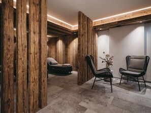 Una habitación con paneles de madera, una cama, dos sillas y un florero con flores.