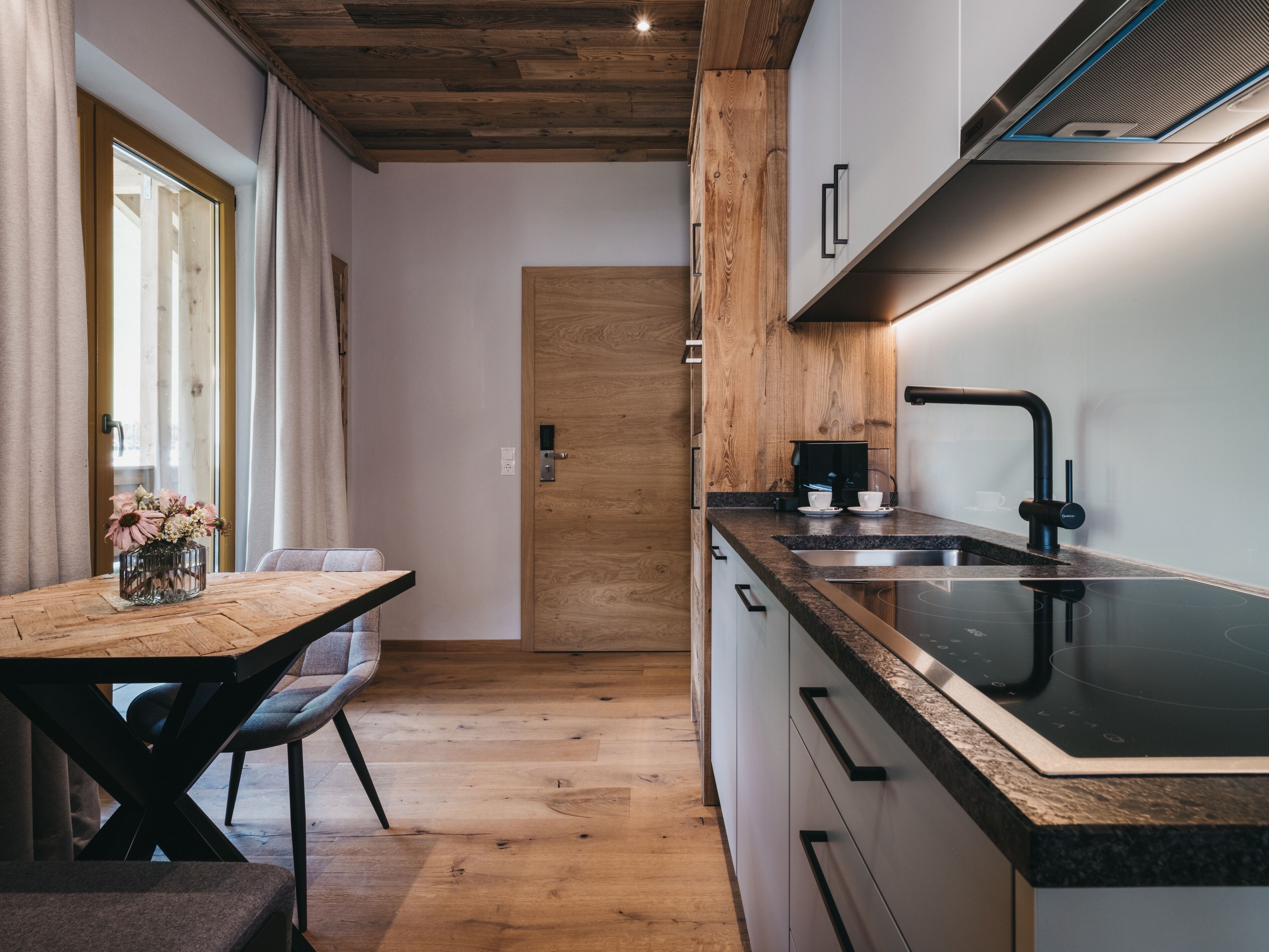 Una cocina moderna con armarios de madera, encimera negra y estufa integrada.
