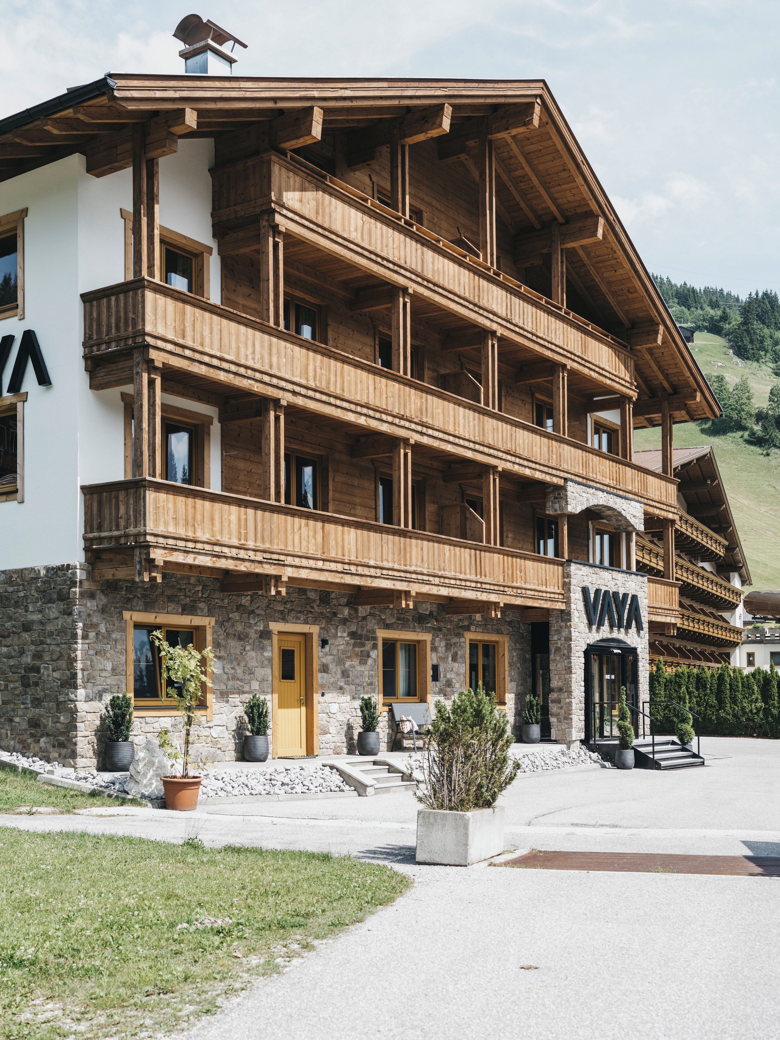 A multi-story wooden building with balconies, a stone facade, and a sign reading 'VAYA'.