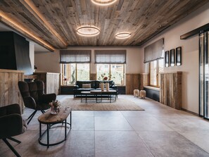 Un salón amplio con techo de madera, ventanas grandes y un sofá moderno.