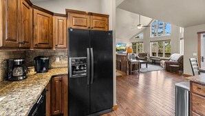 Una cocina moderna con un refrigerador negro, armarios de madera y encimeras de granito.