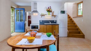 Una cocina con armarios de madera, una estufa y un microondas. Hay una mesa de comedor con un tazón y un florero.