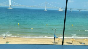 Une chambre d’hôtel avec un lit et une vue sur une plage et un pont.