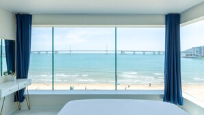 Une chambre avec une grande fenêtre donnant sur une plage et un pont.