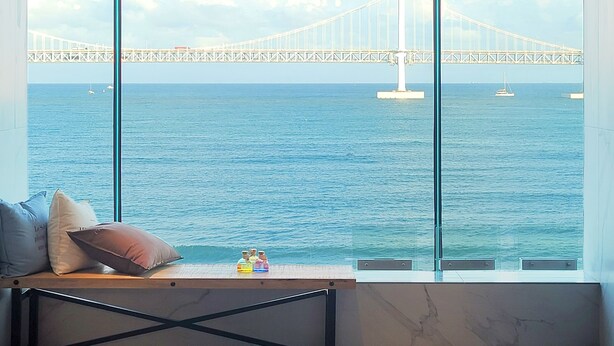 Une chambre moderne dotée d’une grande fenêtre donnant sur un pont et la mer.