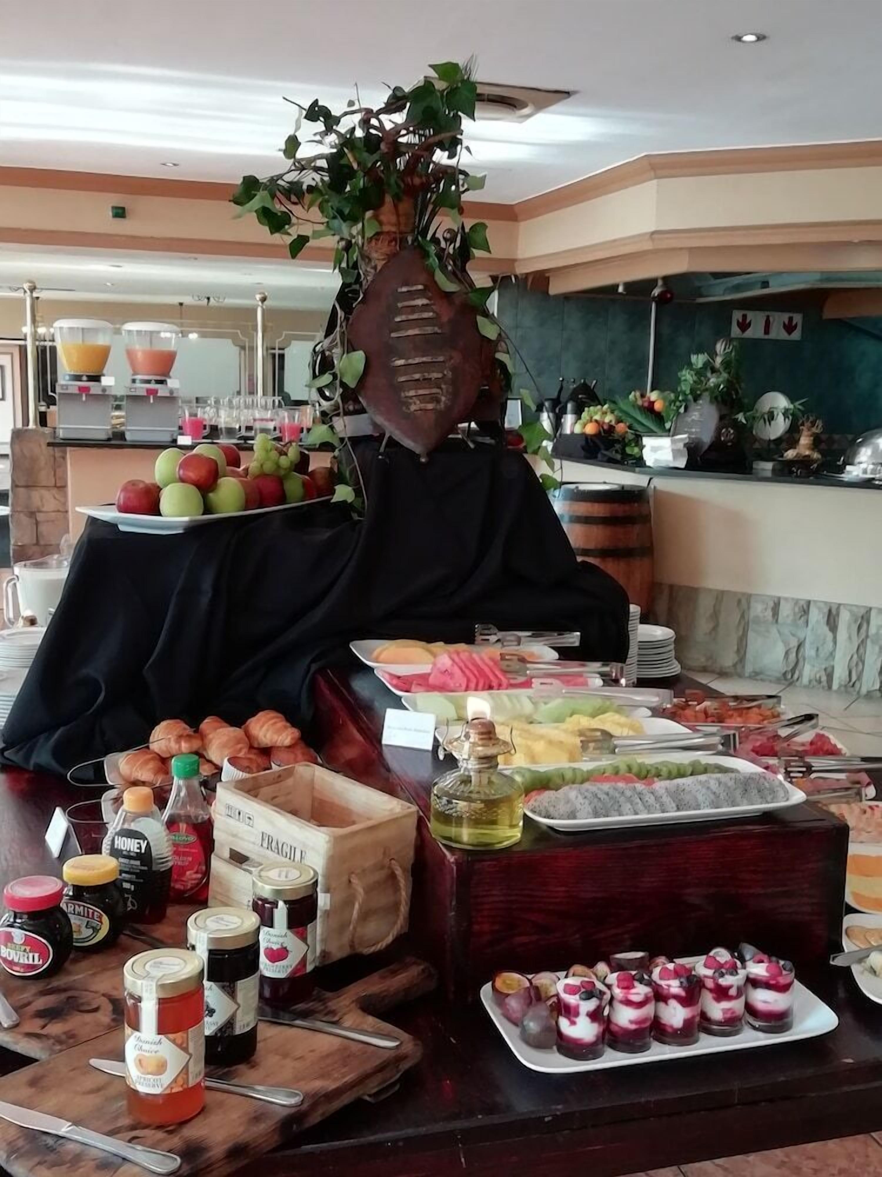 A buffet setup with various food items, including fruits, pastries, and condiments.