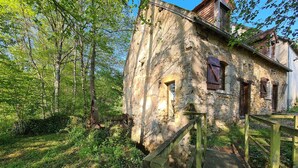 Un bâtiment rustique en pierre, doté d’un escalier en bois menant à une terrasse en bois.