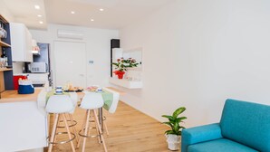 Een moderne keuken met een eethoek, een blauwe bank en een potplant.