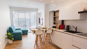 Een moderne keuken met een eethoek, houten vloeren en een groene bank.