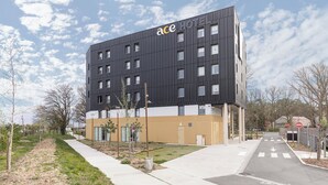 A modern hotel with a flat roof, multiple windows, and a sign reading "ace HOTEL".