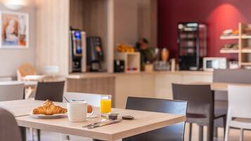 A breakfast table with croissant, coffee, and orange juice.