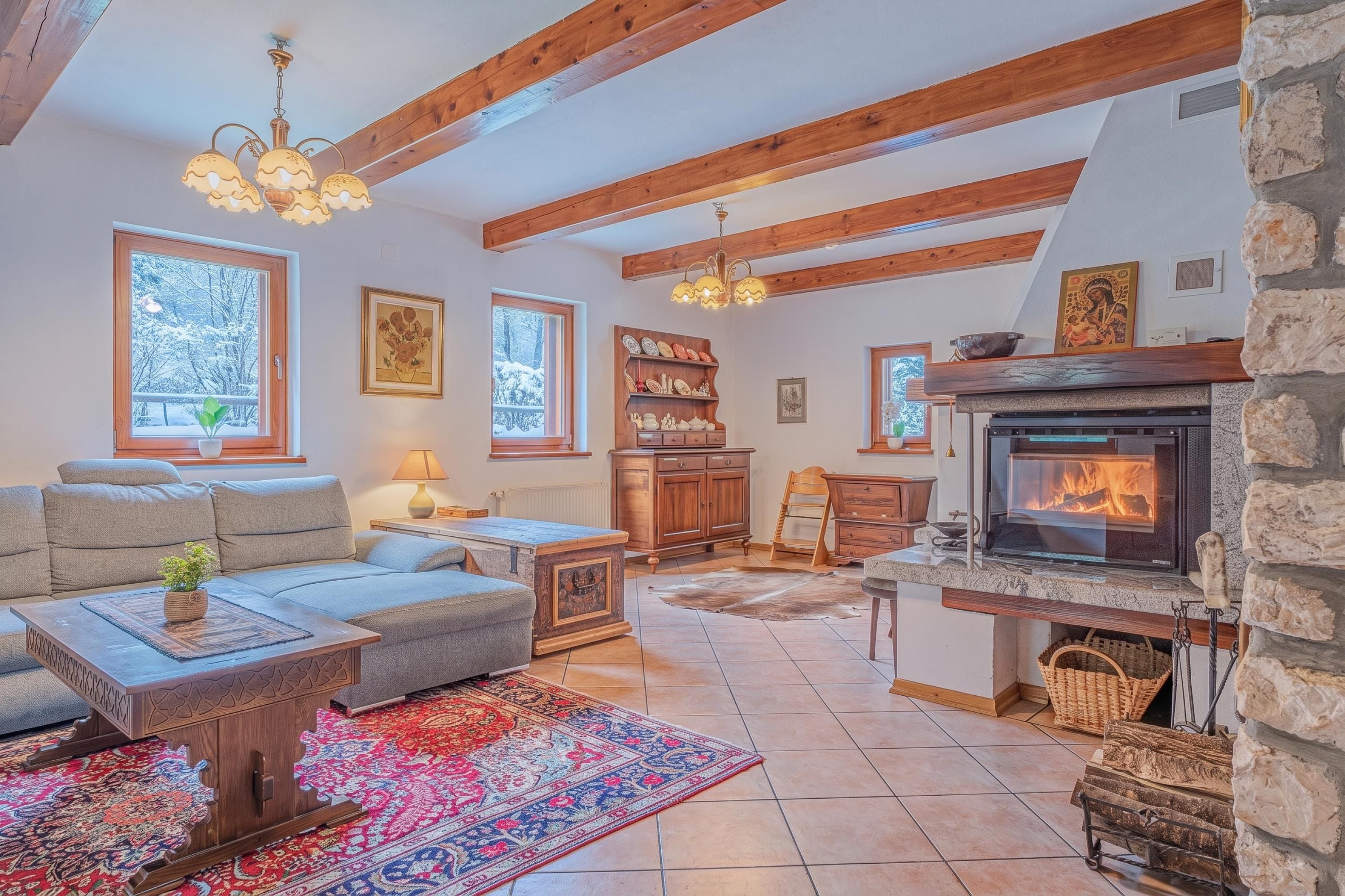 Un salon chaleureux avec une cheminée, des poutres apparentes, un canapé, une table basse et un tapis.