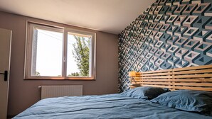 Une chambre à coucher avec un lit, une fenêtre, un radiateur et un mur décoré de motifs.