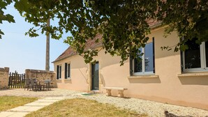 Une maison avec un patio, une table et un banc.