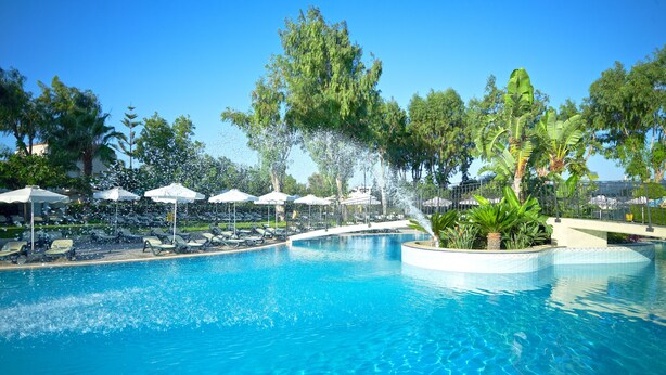 Une piscine dotée de fontaines, de chaises longues et de parasols.