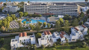 Un complexe hôtelier doté d’une piscine centrale, de plusieurs bâtiments et offrant une vue sur la mer.