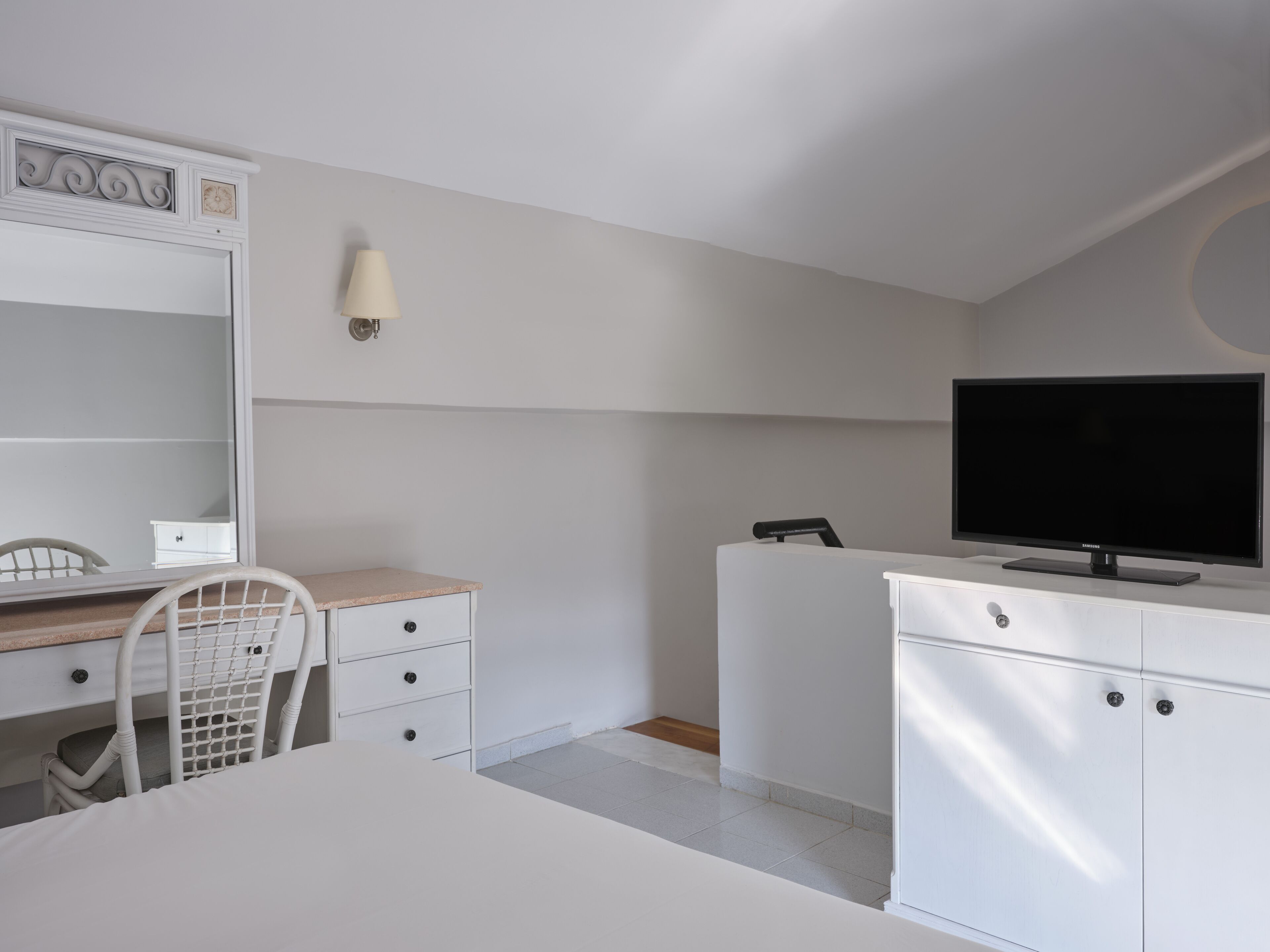 Ein modernes Schlafzimmer mit Bett, Schreibtisch, Stuhl, Fernseher und Kleiderschrank.