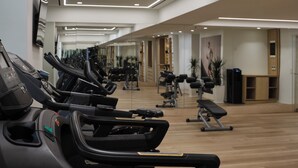 Une salle de sport équipée de tapis de course, d’appareils de musculation et de tapis de sol pour les exercices.