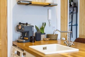A kitchen with a coffee machine, a sink, a phone, and a potted plant. - Stylish Flat on Beautiful Clifton Street, Parking (Clifton)