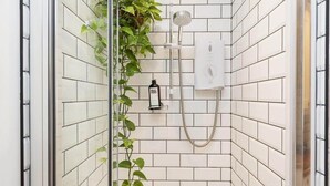 A shower with white tiles, a handheld showerhead, and a wall-mounted control panel. - Stylish Flat on Beautiful Clifton Street, Parking (Clifton)