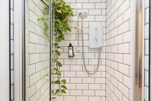 A shower with white tiles, a handheld showerhead, and a wall-mounted control panel. - Stylish Flat on Beautiful Clifton Street, Parking (Clifton)