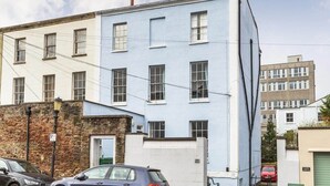 A multi-story building with a light blue facade, several windows, and a stone base. - Stylish Flat on Beautiful Clifton Street, Parking (Clifton)