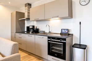 Cocina moderna con horno empotrado, cafetera y un reloj en la pared.