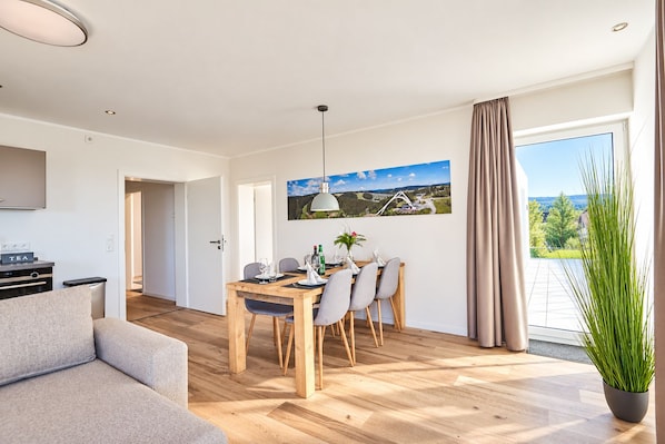 Una sala de estar moderna con comedor, cocina y balcón con vistas.