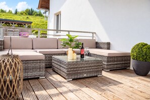 A sunlit outdoor seating area with wicker furniture, a potted plant, and a bottle of wine. - Smart Resorts – Haus Opal – Holiday flat 403 with 2 bedrooms and a balcony, slee (Winterberg)