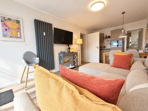 A modern living room with a sofa, a television, and a dining area. - Smart Resorts - Haus Saphir - Ferienwohnung 508 mit 2 Schlafzimmern, max (Winterberg)