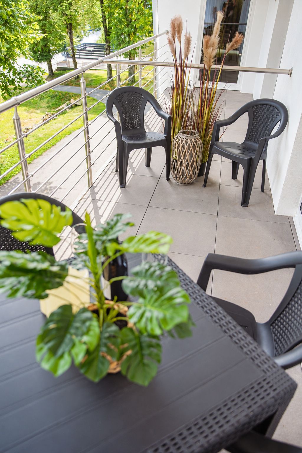 Ein Balkon mit zwei schwarzen Stühlen, einem Tisch und einem Blumentopf.