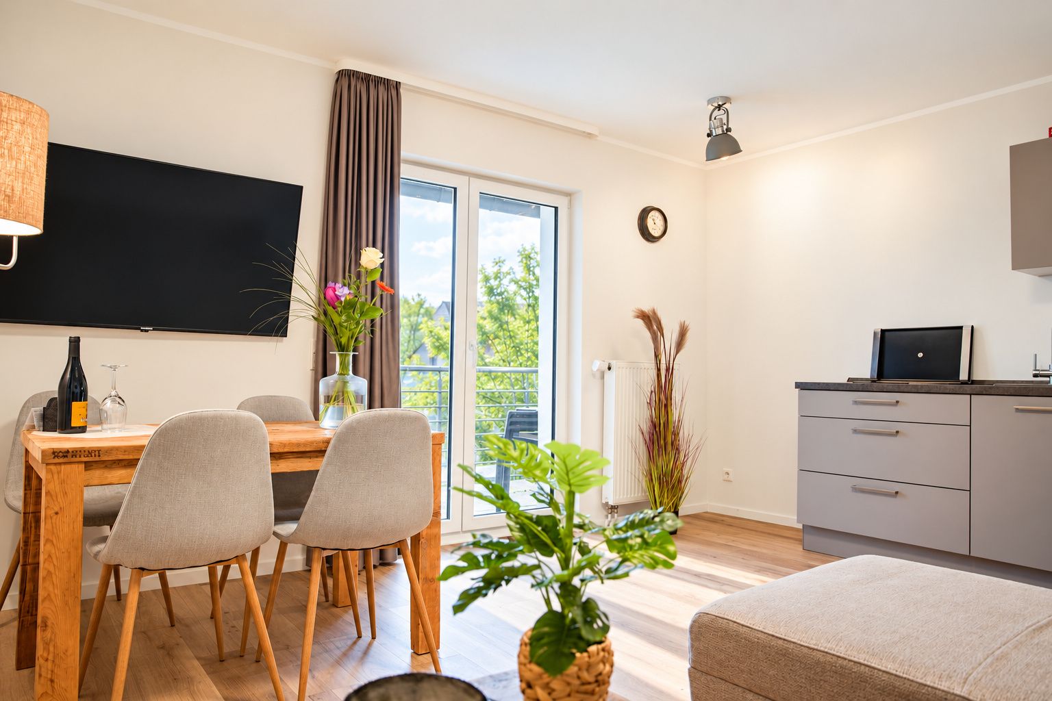 A modern living room with a dining area, a kitchen, and a balcony with a view.